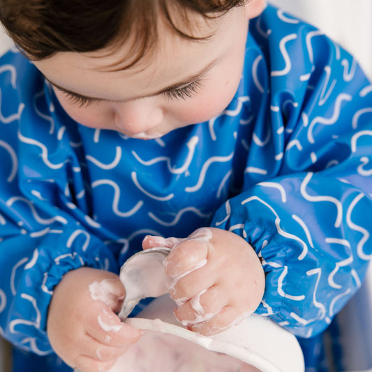 Abibi long sleeve smock bib, bright playful print, keeps clothes clean during mealtimes